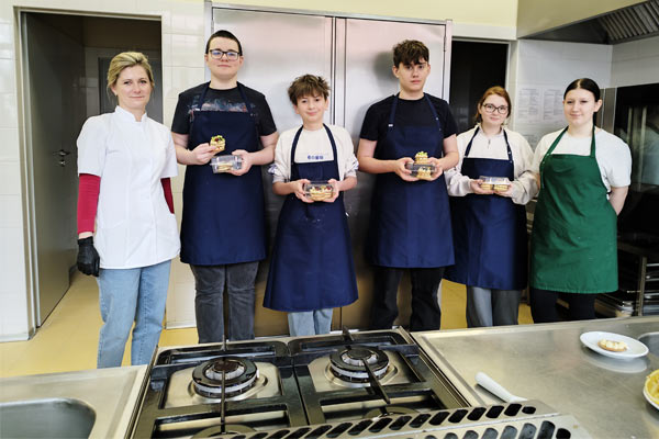 Uczniowie z ciastem stoją w kuchni