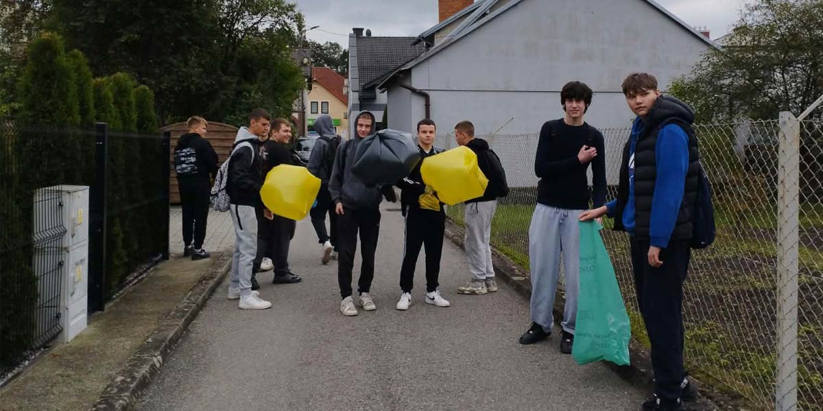 Uczniowie stoją trzymając worki ze śmieciami