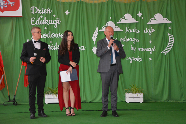 Stoi dwoje uczniów i dyrektor szkoły na scenie